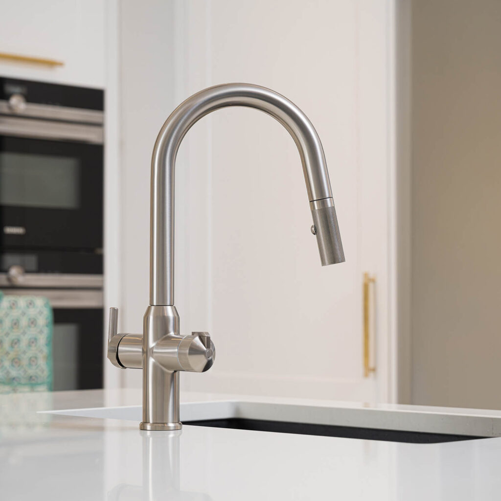 Quel Ultra Plus 4-in-1 instant boiling water tap in brushed nickel, shown installed beside a black undermount sink with the pull-out spray head docked and textured dual controls visible in a modern kitchen.