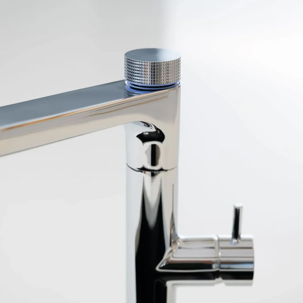 Close-up of the Quel Ultimo 6-in-1 water tap in chrome, highlighting the textured knurled selector knob with blue LED ring and the cylindrical side lever control, against a plain white background