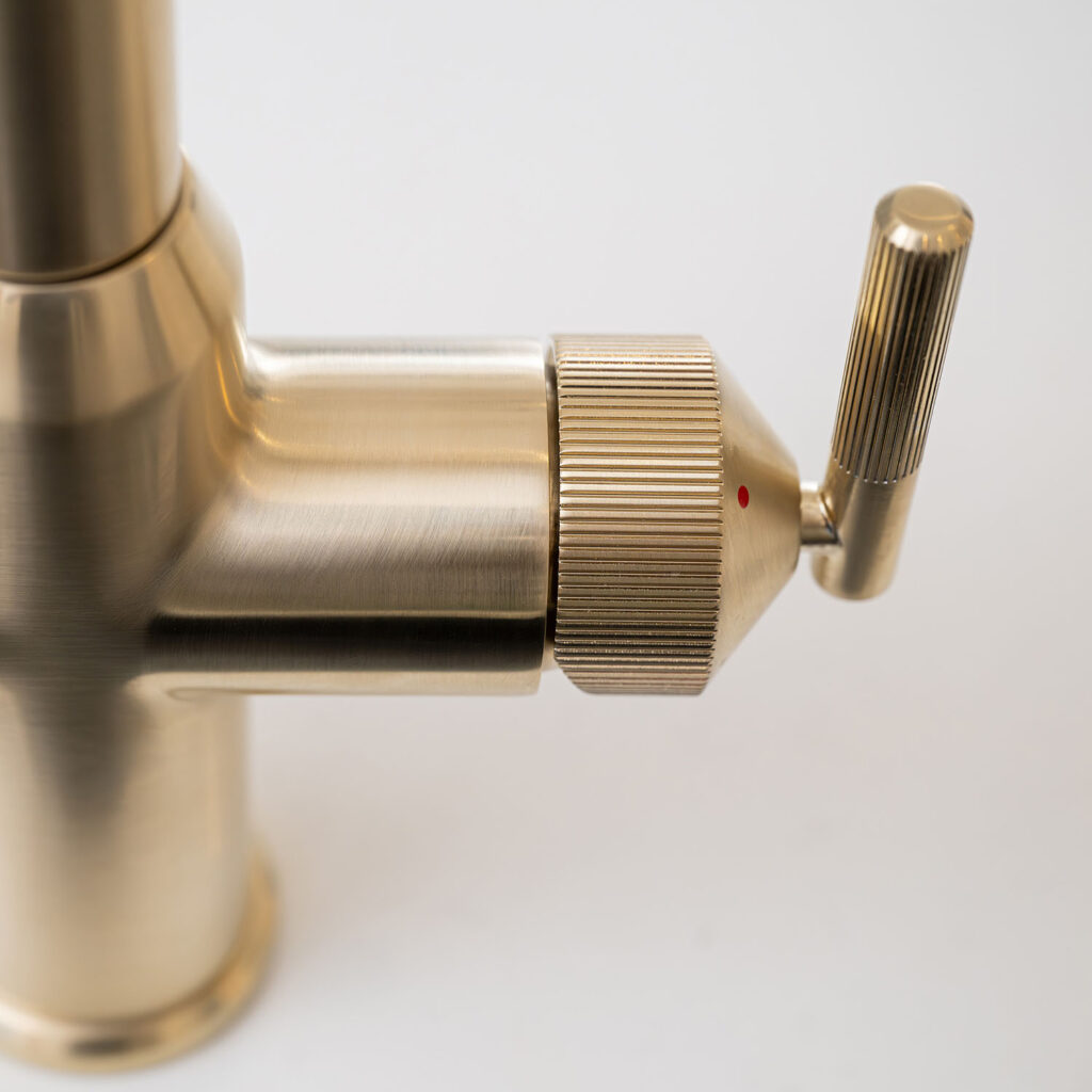 Quel Ultra Plus 4-in-1 instant boiling water tap in brushed brass, close-up of the lever control with textured detailing and red temperature indicator.